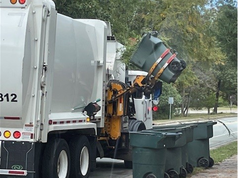 Picture shows solid waste tuck lifting a residential roll-out waste container.