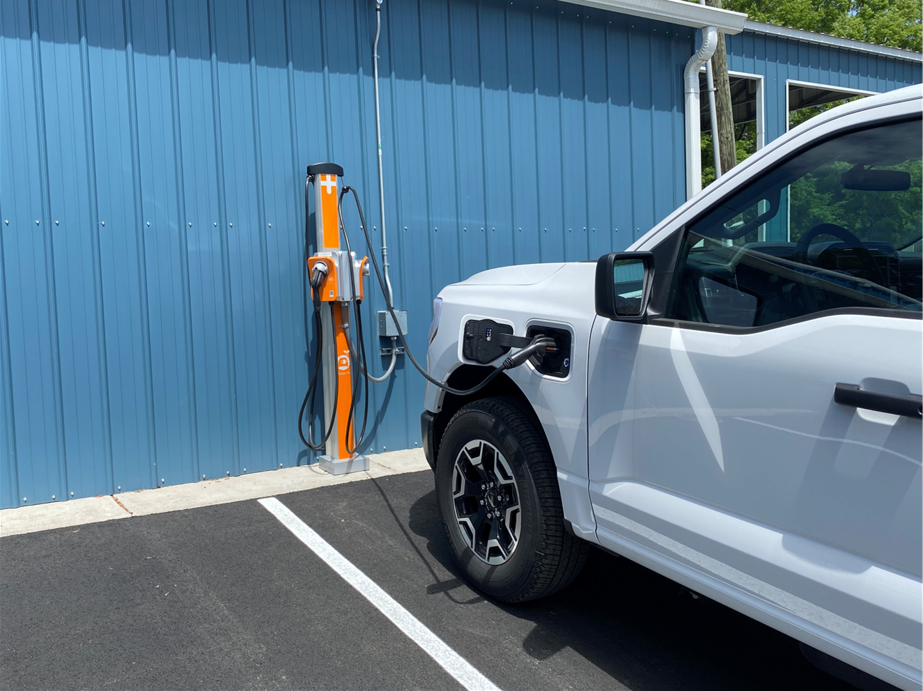Picture shows a white electric truck plugged into an electric vehicle car charger 